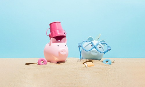 Pink and blue piggy banks on the beach.
